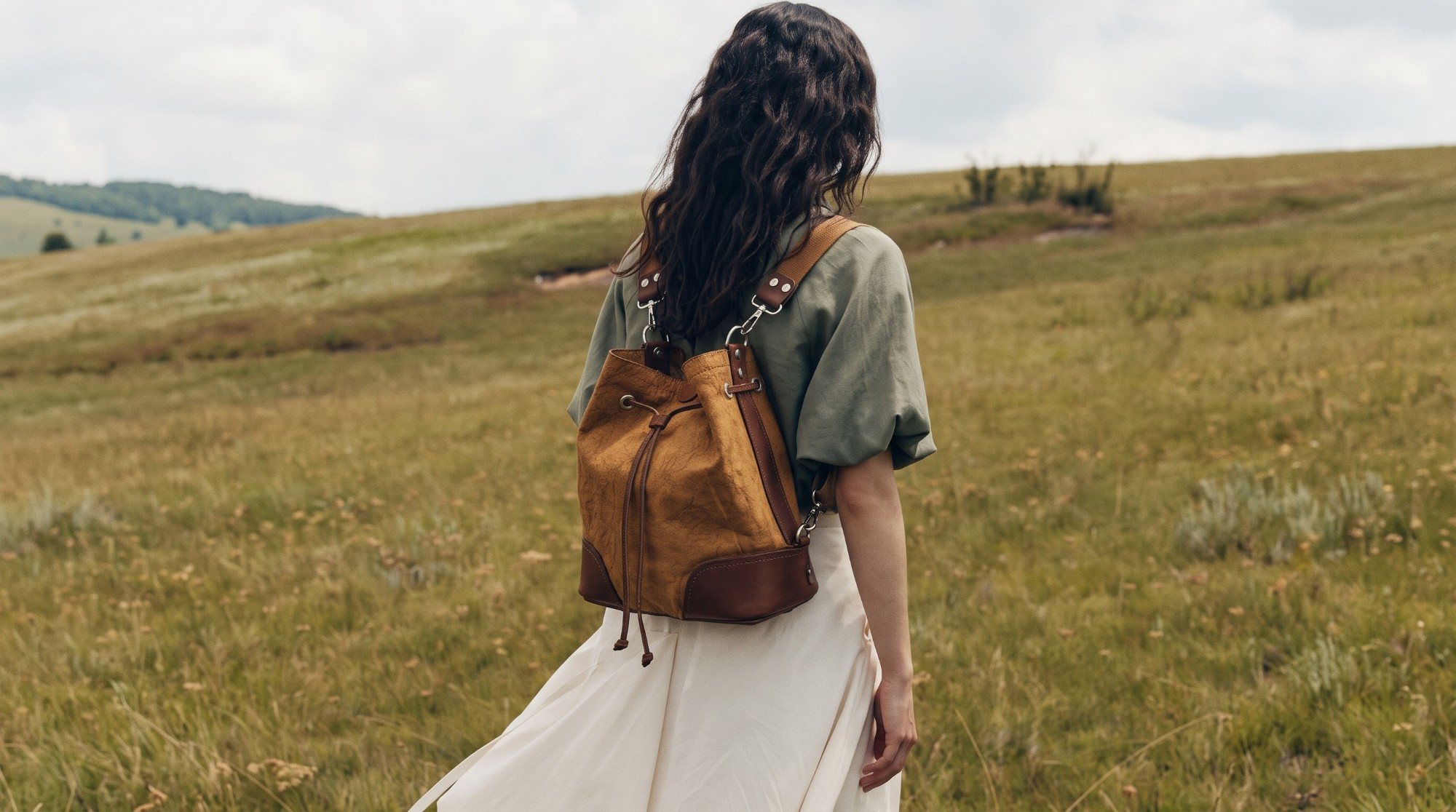 Mujer caminando por un campo con la Marinera Suela Patinada llevada como mochila